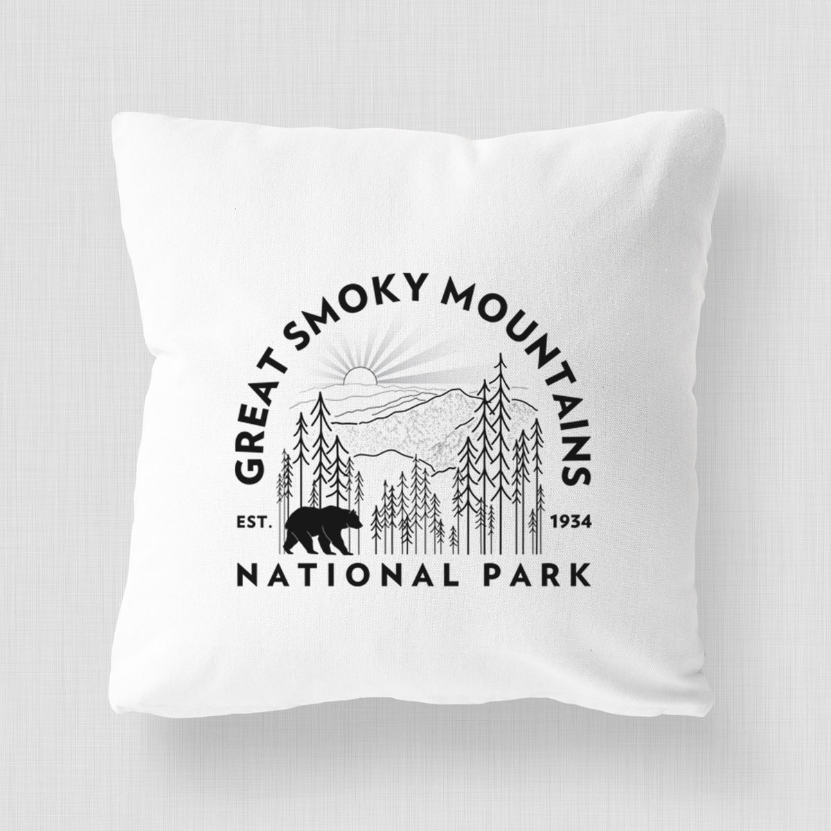 White pillow cover printed with a round badge of mountains, pine trees and a black bear, with the words Great Smoky Mountains National Park, Est. 1934.