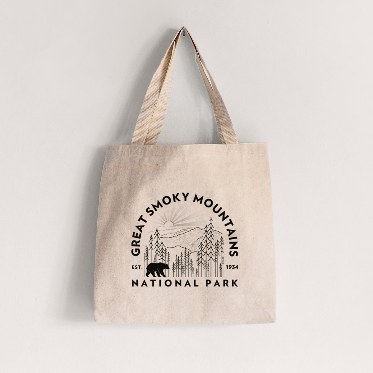 Natural canvas tote bag printed with a round badge of mountains, pine trees and a black bear, with the words Great Smoky Mountains National Park, Est. 1934.