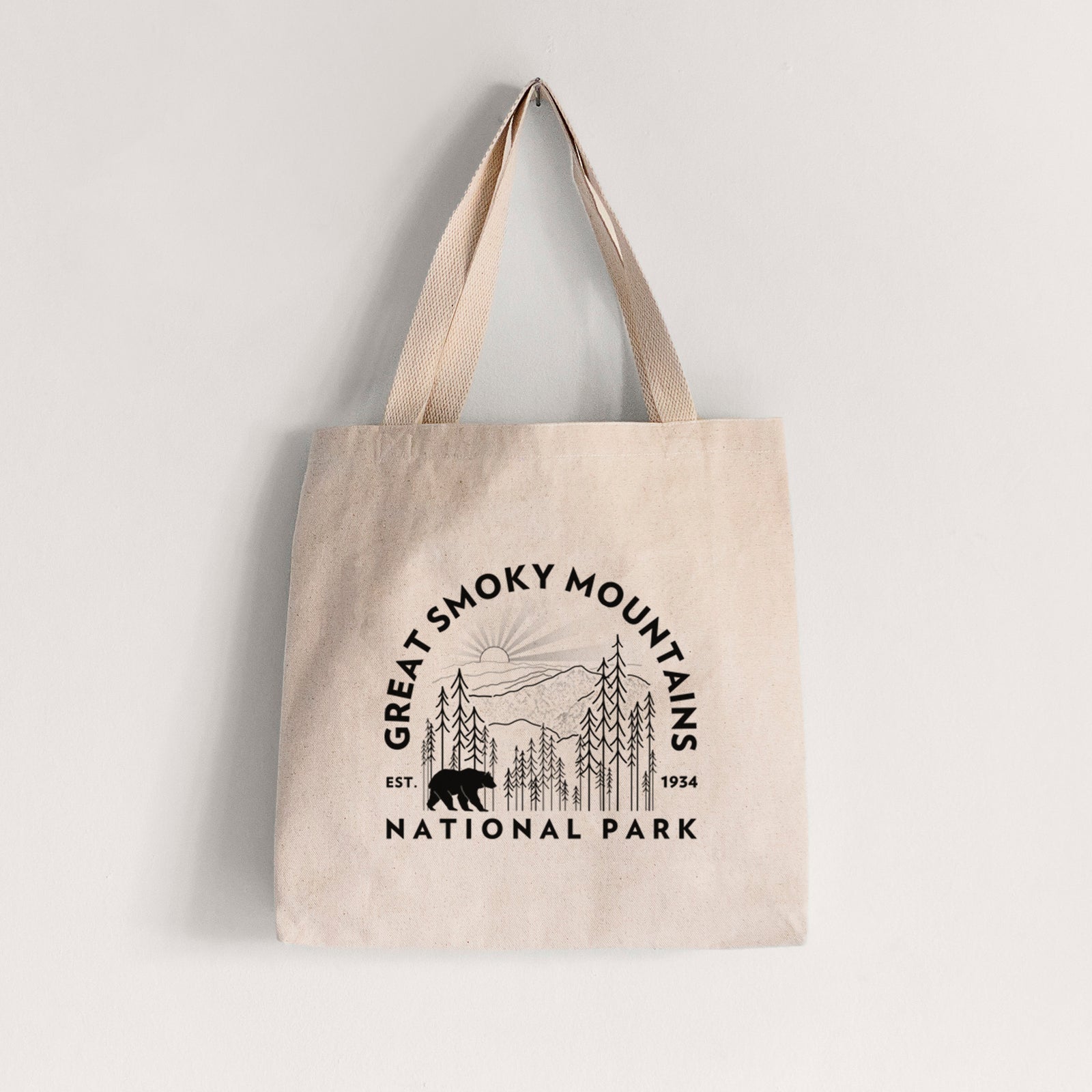 Natural canvas tote bag printed with a round badge of mountains, pine trees and a black bear, with the words Great Smoky Mountains National Park, Est. 1934.