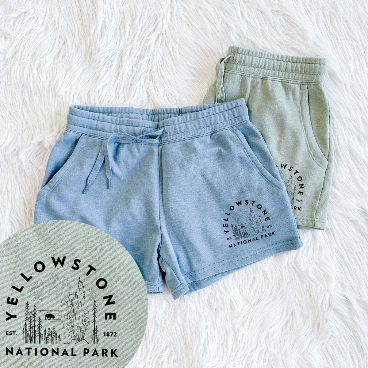 Two pairs of Cali Wave shorts in different colors printed with a round badge of a waterfall, pine trees and a bison, with the words Yellowstone National Park, Est. 1872, with a close-up of the print.