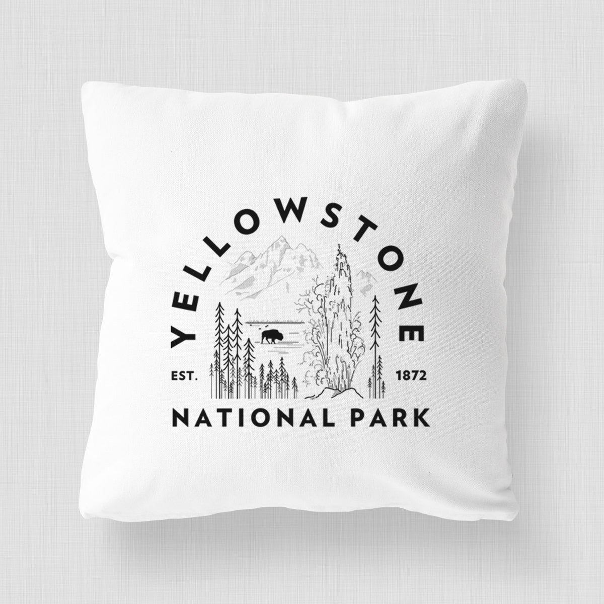 White pillow cover printed with a round badge of a waterfall, pine trees and a bison, with the words Yellowstone National Park, Est. 1872.