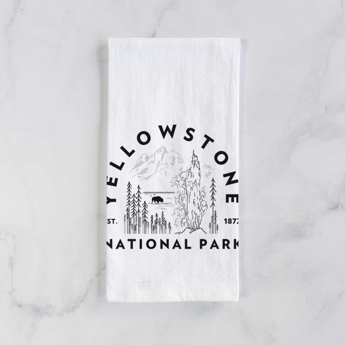 White cotton tea towel laid flat on marble, printed with a round badge of a waterfall, pine trees and a bison, with the words Yellowstone National Park, Est. 1872.