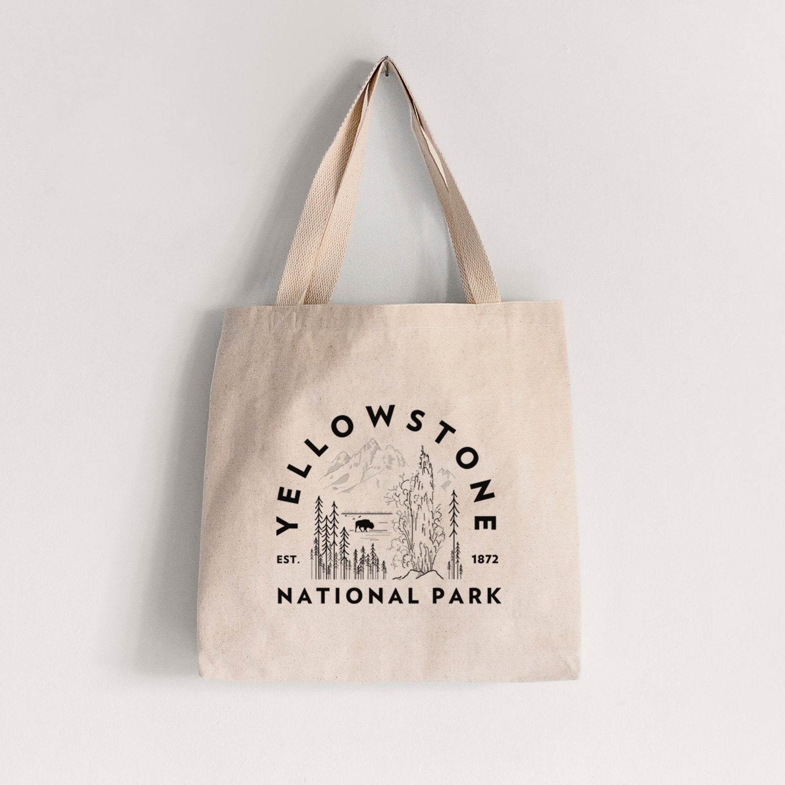 Natural canvas tote bag printed with a round badge of a waterfall, pine trees and a bison, with the words Yellowstone National Park, Est. 1872.