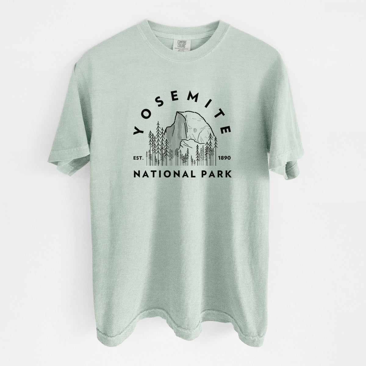 Bay green Comfort Colors t-shirt laid flat, printed with a round badge of Half Dome and pine trees, with the words Yosemite National Park, Est. 1890.