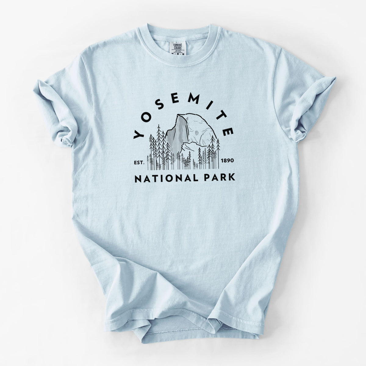 Chambray blue Comfort Colors t-shirt laid flat, printed with a round badge of Half Dome and pine trees, with the words Yosemite National Park, Est. 1890.