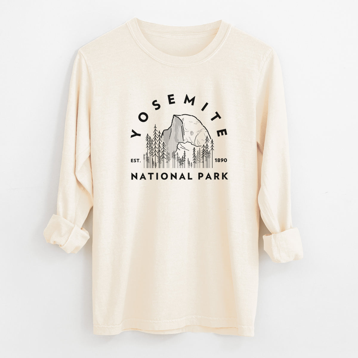 Ivory Comfort Colors long sleeve shirt laid flat with the cuffs rolled, printed with a round badge of Half Dome and pine trees, with the words Yosemite National Park, Est. 1890.