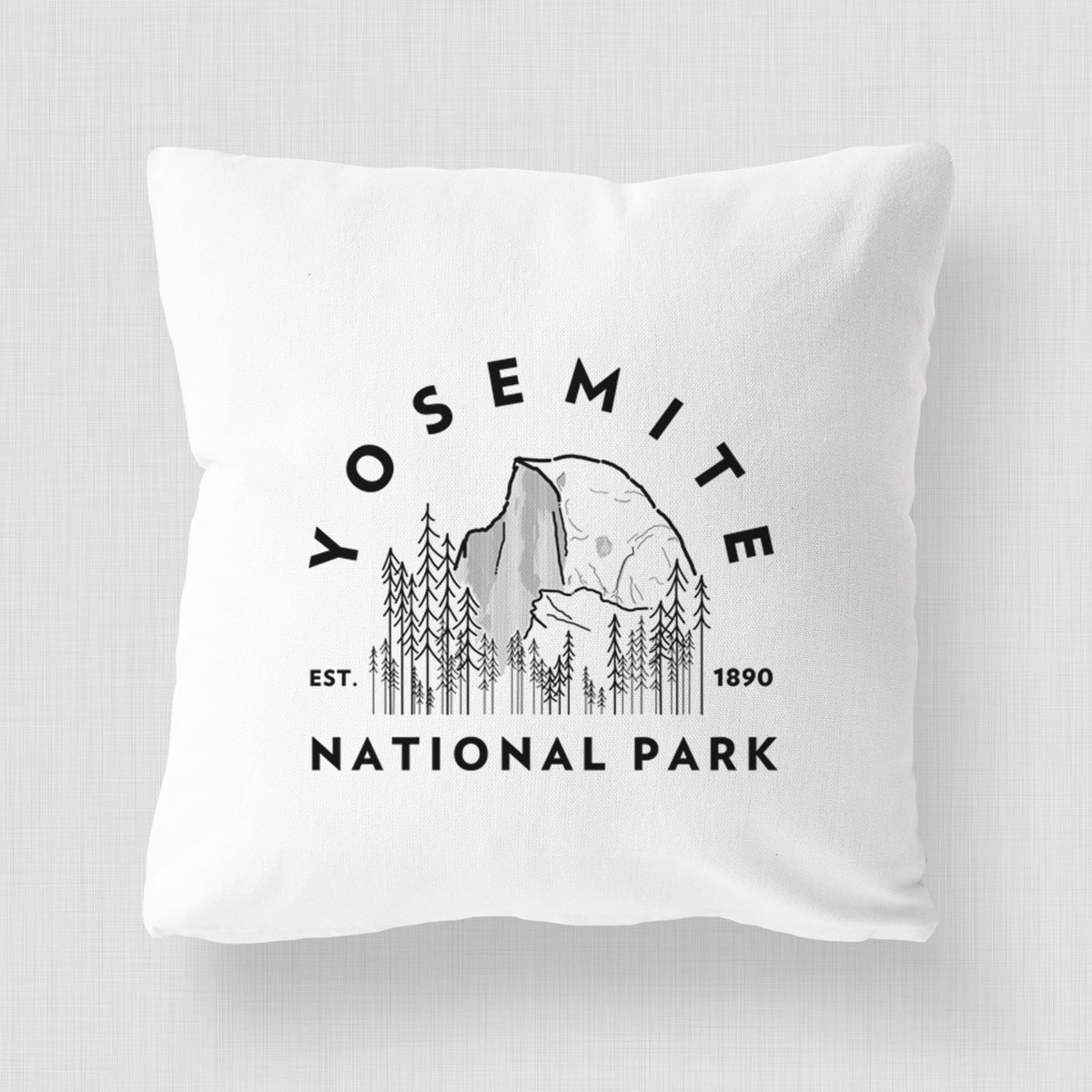White pillow cover printed with a round badge of Half Dome and pine trees, with the words Yosemite National Park, Est. 1890.