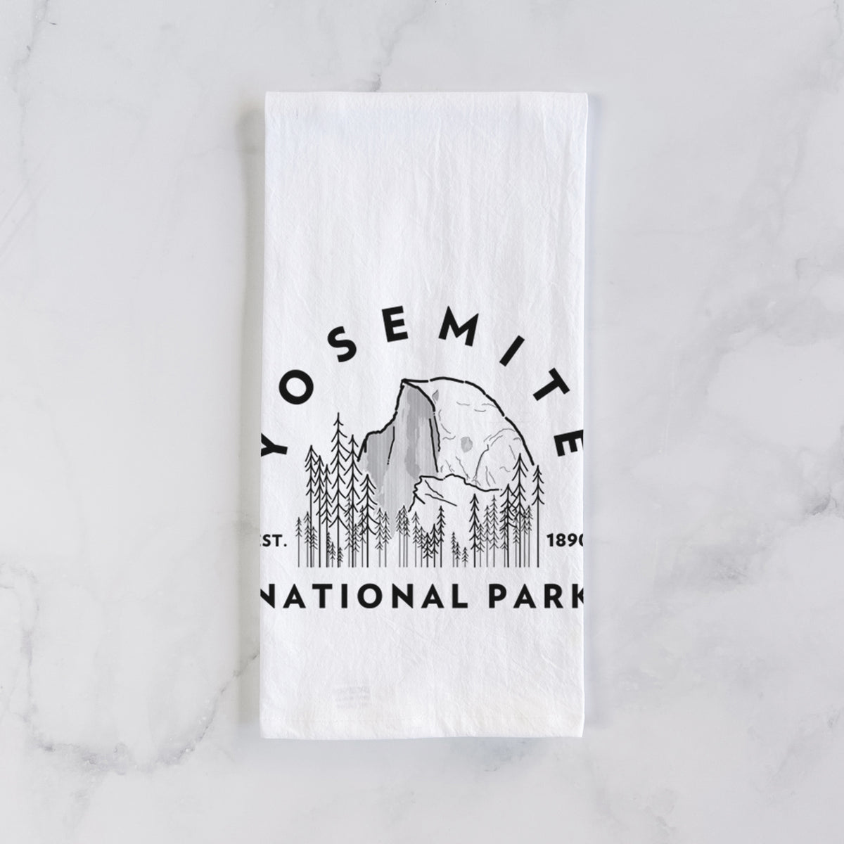 White cotton tea towel laid flat on marble, printed with a round badge of Half Dome and pine trees, with the words Yosemite National Park, Est. 1890.
