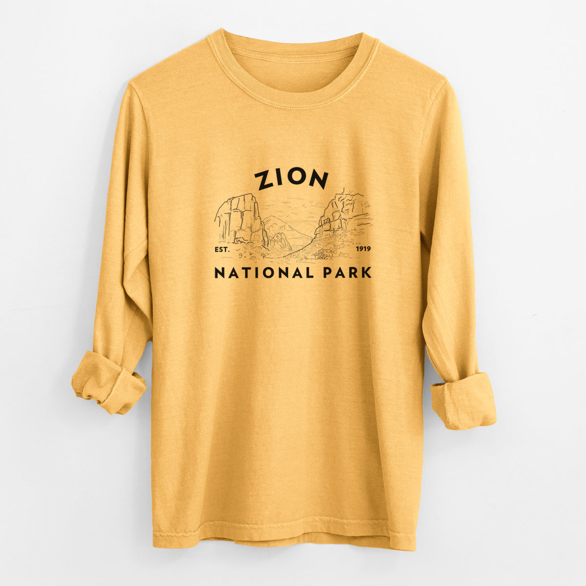 Golden wheat yellow Comfort Colors long sleeve shirt laid flat with the cuffs rolled, printed with a round badge of canyon walls, with the words Zion National Park, Est. 1919.
