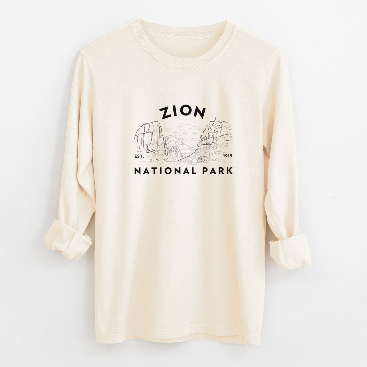 Ivory Comfort Colors long sleeve shirt laid flat with the cuffs rolled, printed with a round badge of canyon walls, with the words Zion National Park, Est. 1919.