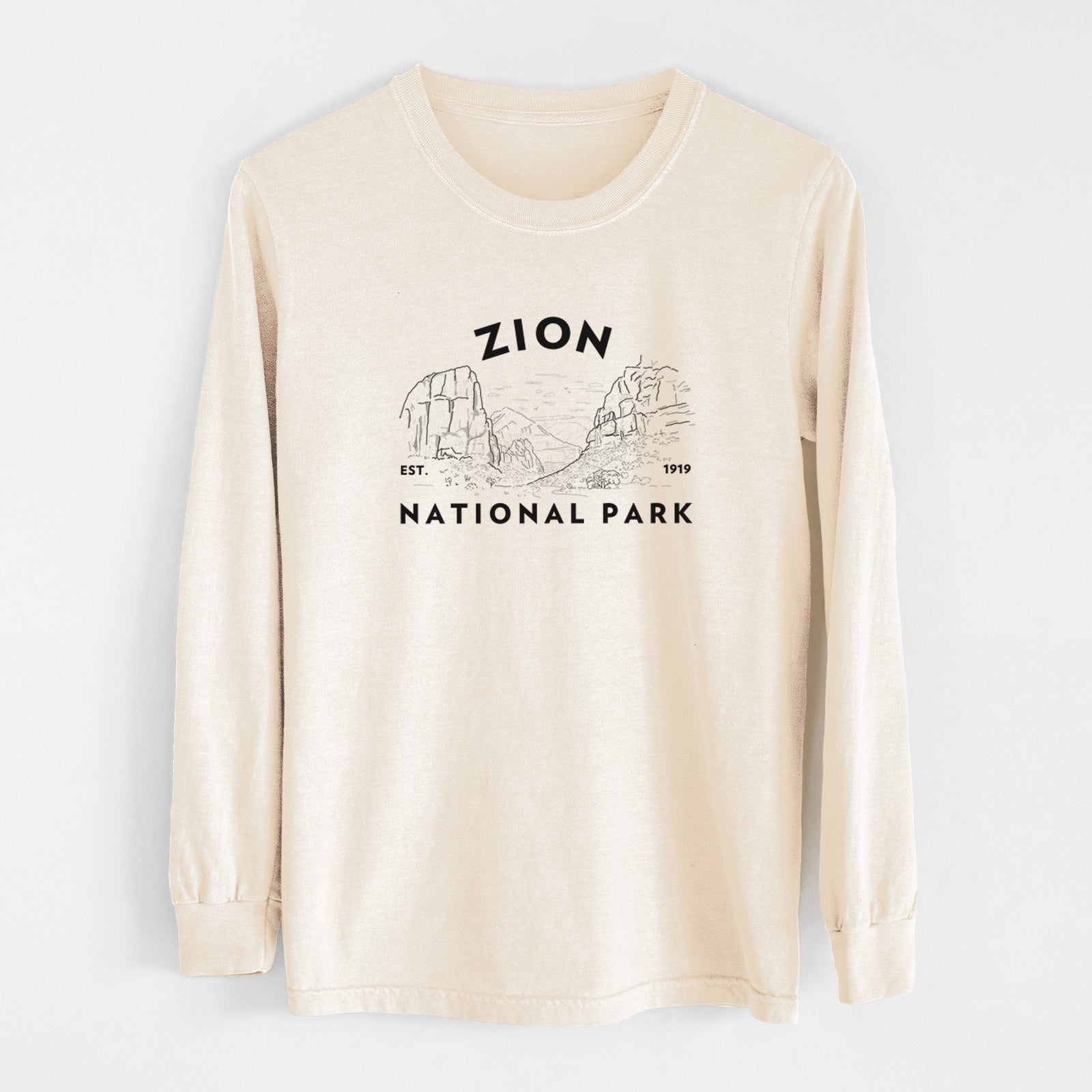 Ivory Comfort Colors long sleeve shirt laid flat, printed with a round badge of canyon walls, with the words Zion National Park, Est. 1919.
