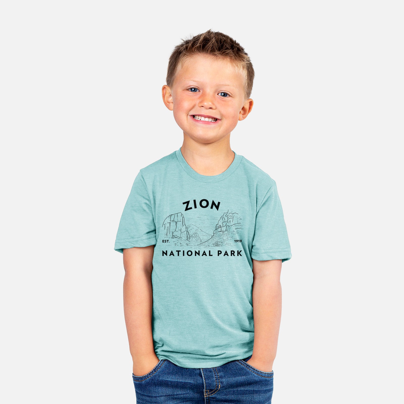 Two youth t-shirts in different colors on hangers, printed with a round badge of canyon walls, with the words Zion National Park, Est. 1919.