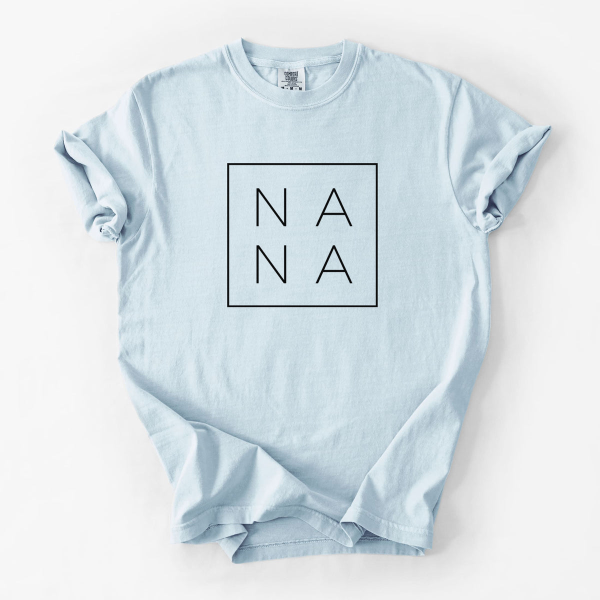 Chambray blue Comfort Colors t-shirt laid flat, printed with the word NANA in thin black letters stacked inside a square outline.
