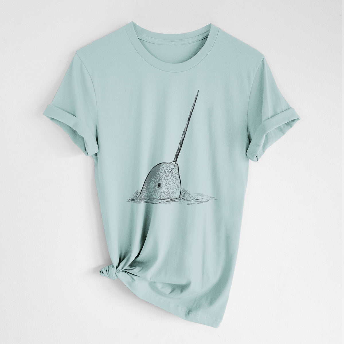 Dusty blue lightweight cotton t-shirt laid flat with the sleeves rolled, printed with a black ink illustration of a narwhal with its long spiral tusk pointing upward.