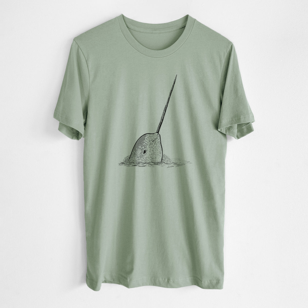 Sage green lightweight cotton t-shirt laid flat, printed with a black ink illustration of a narwhal with its long spiral tusk pointing upward.