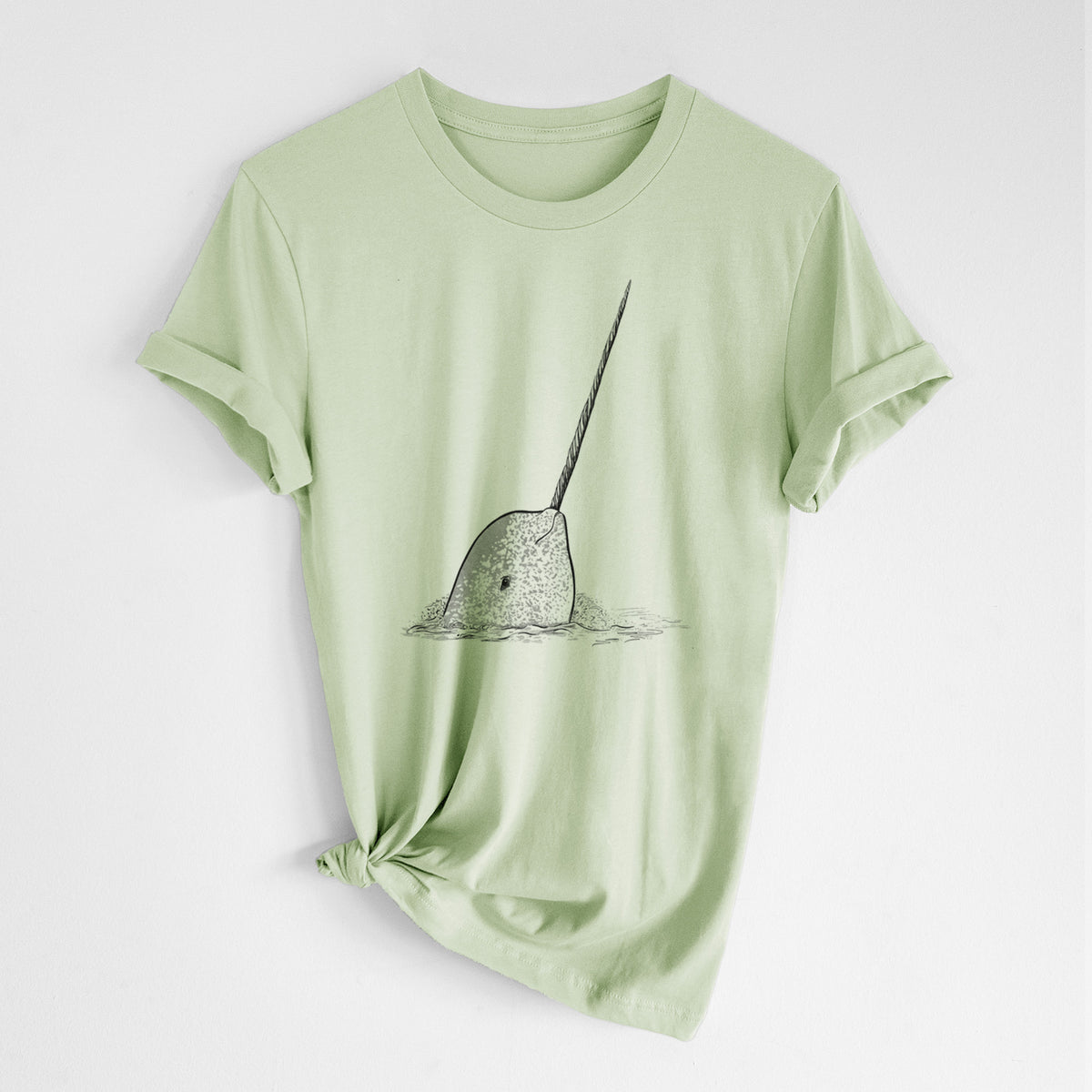 Spring green lightweight cotton t-shirt laid flat with the sleeves rolled, printed with a black ink illustration of a narwhal with its long spiral tusk pointing upward.