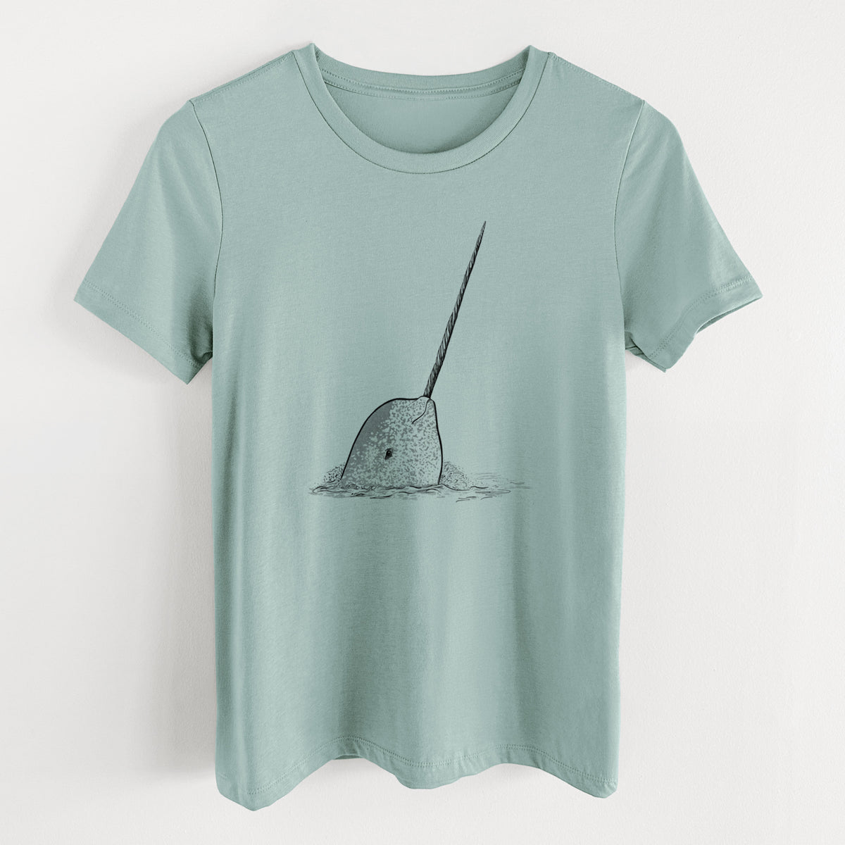 Dusty blue women's relaxed fit cotton t-shirt laid flat, printed with a black ink illustration of a narwhal with its long spiral tusk pointing upward.