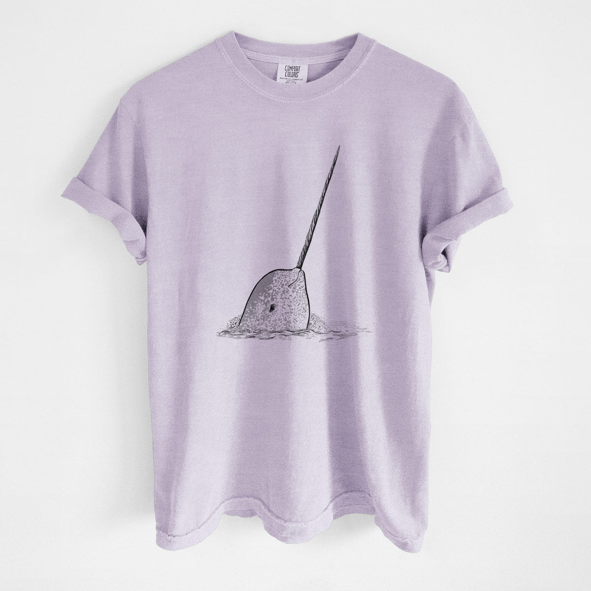 Orchid purple Comfort Colors t-shirt laid flat, printed with a black ink illustration of a narwhal with its long spiral tusk pointing upward.