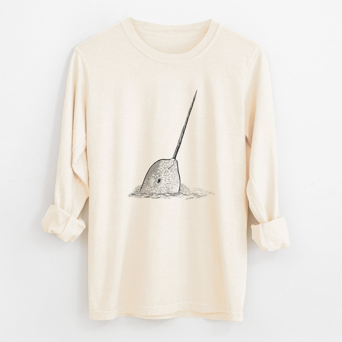 Ivory Comfort Colors long sleeve shirt laid flat with the cuffs rolled, printed with a black ink illustration of a narwhal with its long spiral tusk pointing upward.