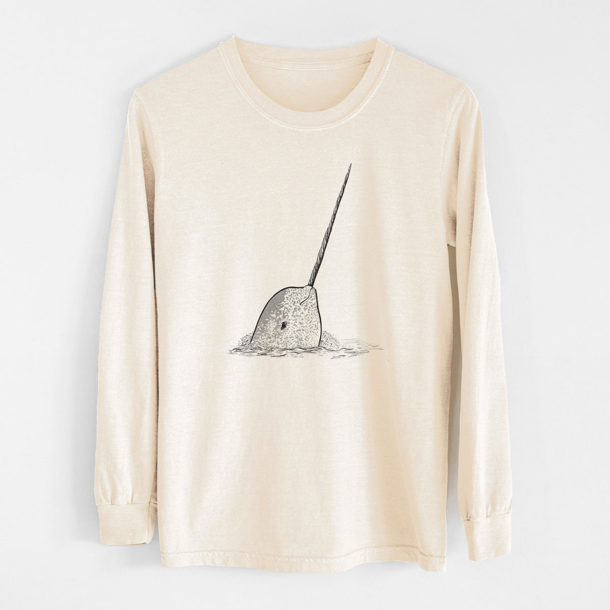 Ivory Comfort Colors long sleeve shirt laid flat, printed with a black ink illustration of a narwhal with its long spiral tusk pointing upward.