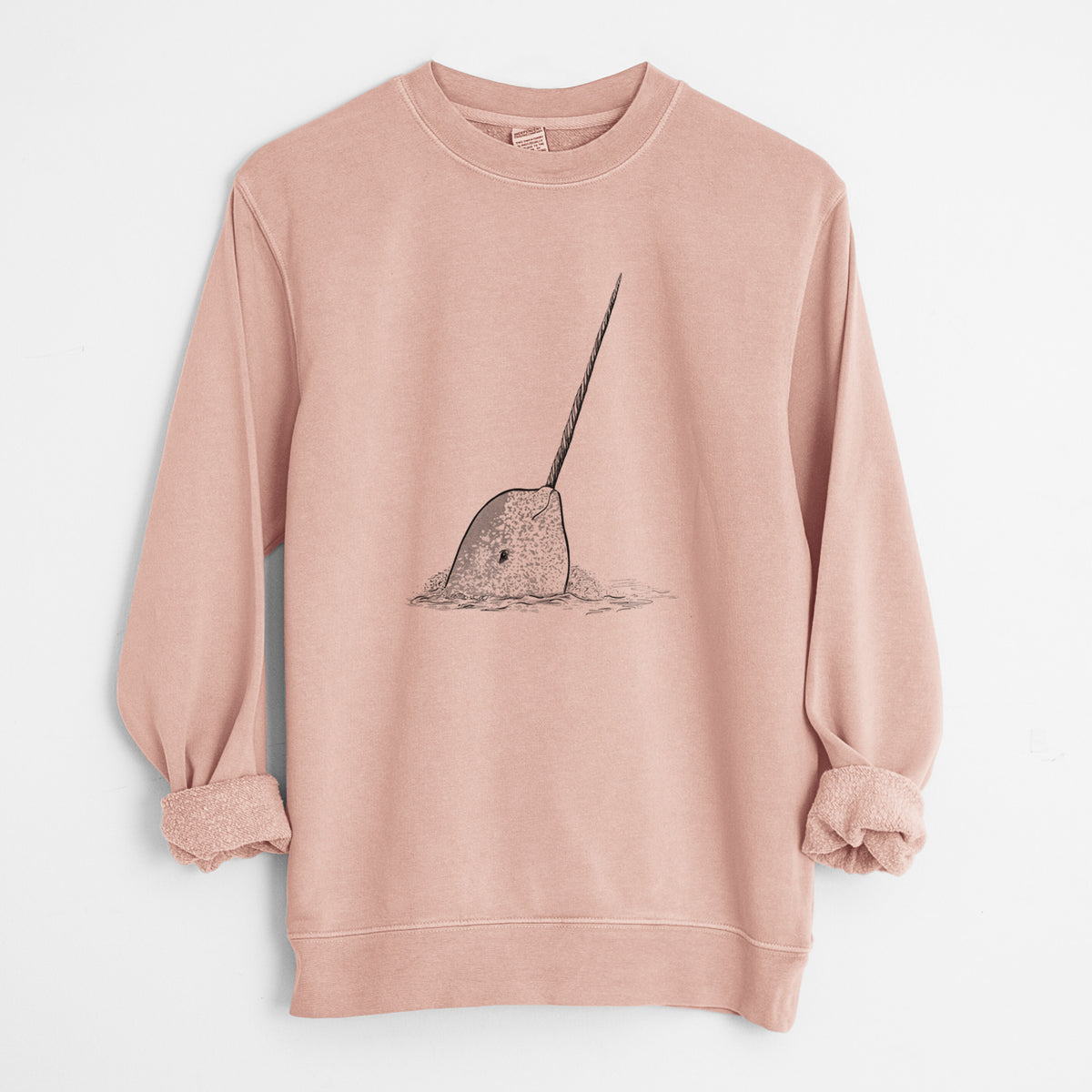 Dusty pink pigment dyed crewneck sweatshirt laid flat with the sleeves rolled, printed with a black ink illustration of a narwhal with its long spiral tusk pointing upward.