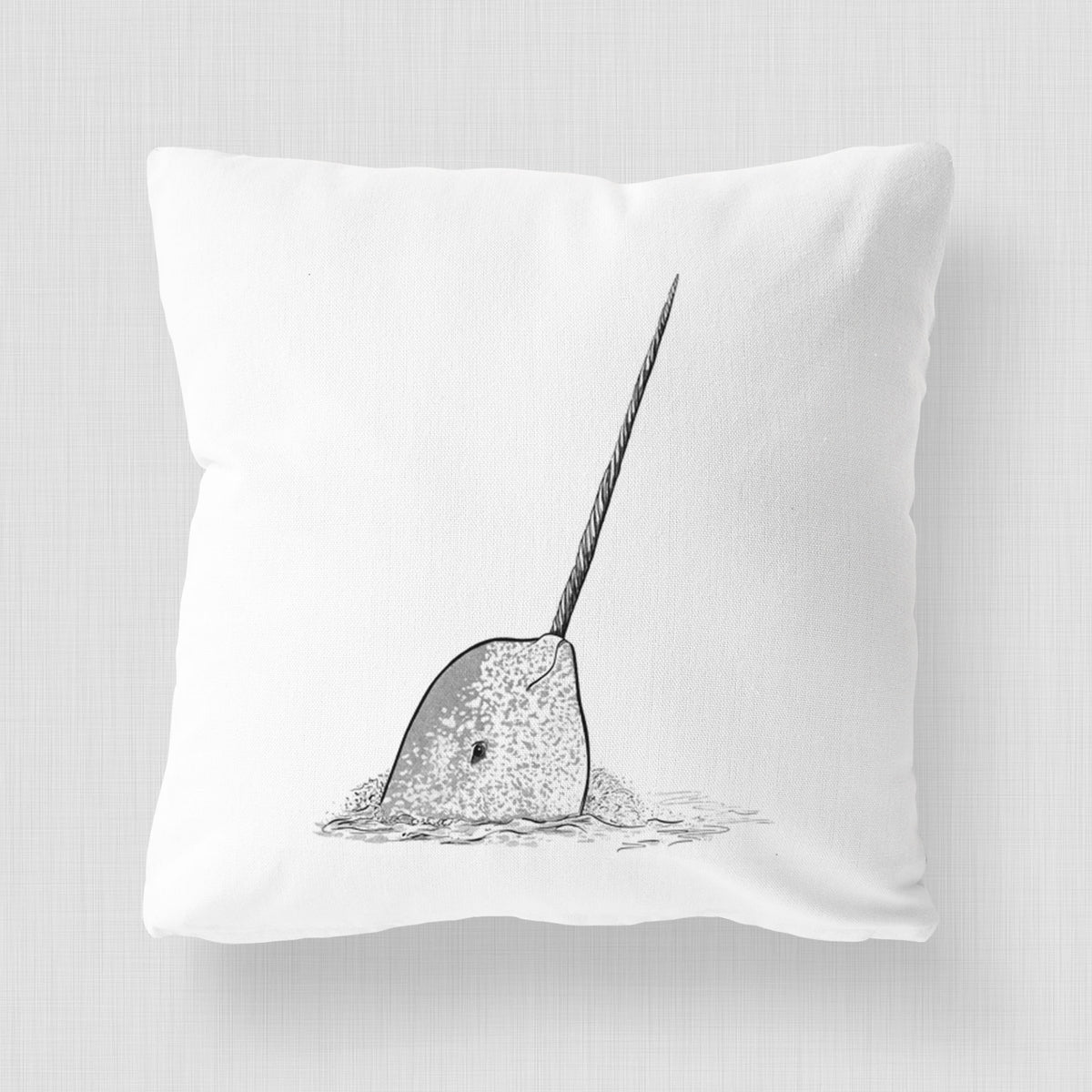 White pillow cover printed with a black ink illustration of a narwhal with its long spiral tusk pointing upward.