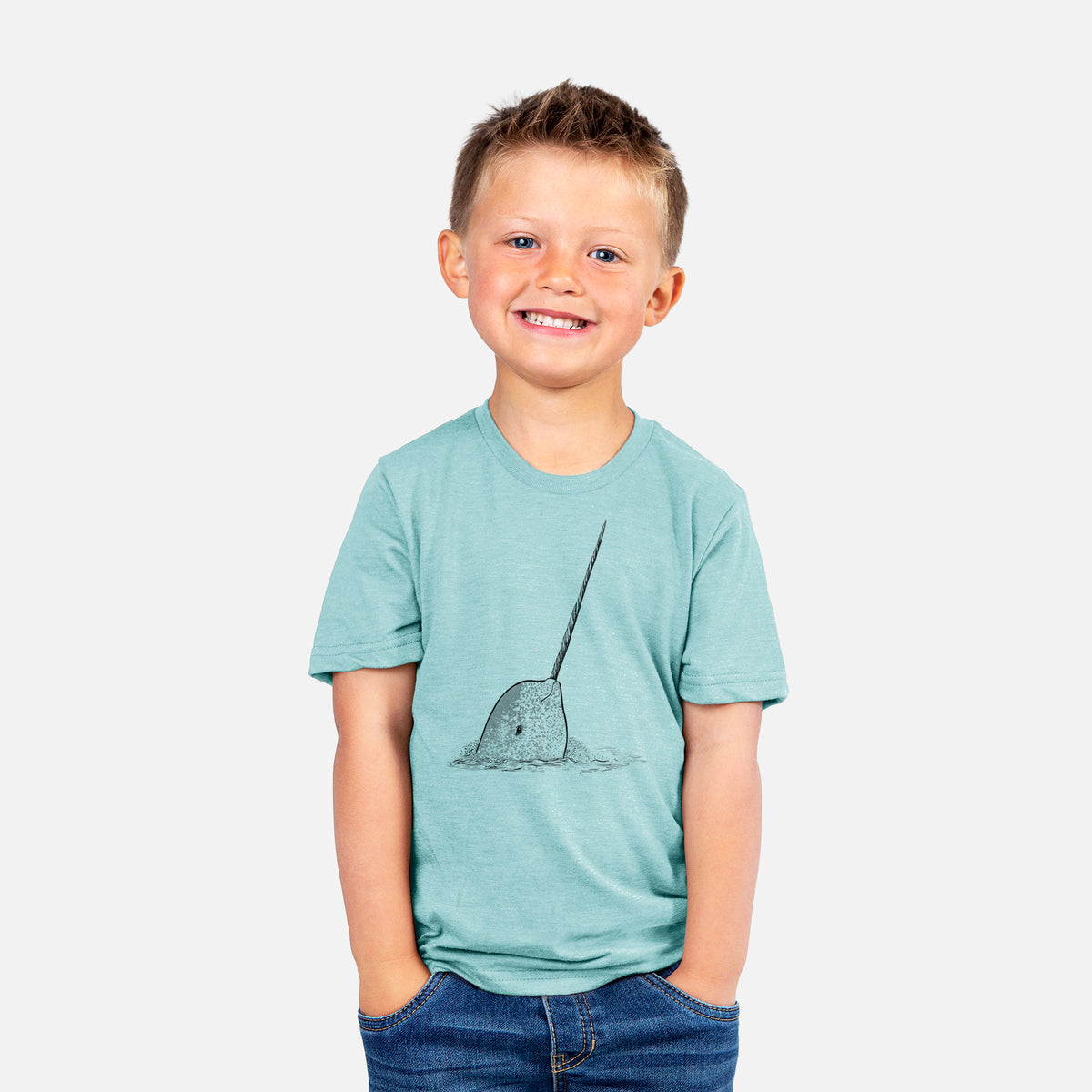 Smiling boy wearing a youth t-shirt printed with a black ink illustration of a narwhal with its long spiral tusk pointing upward.