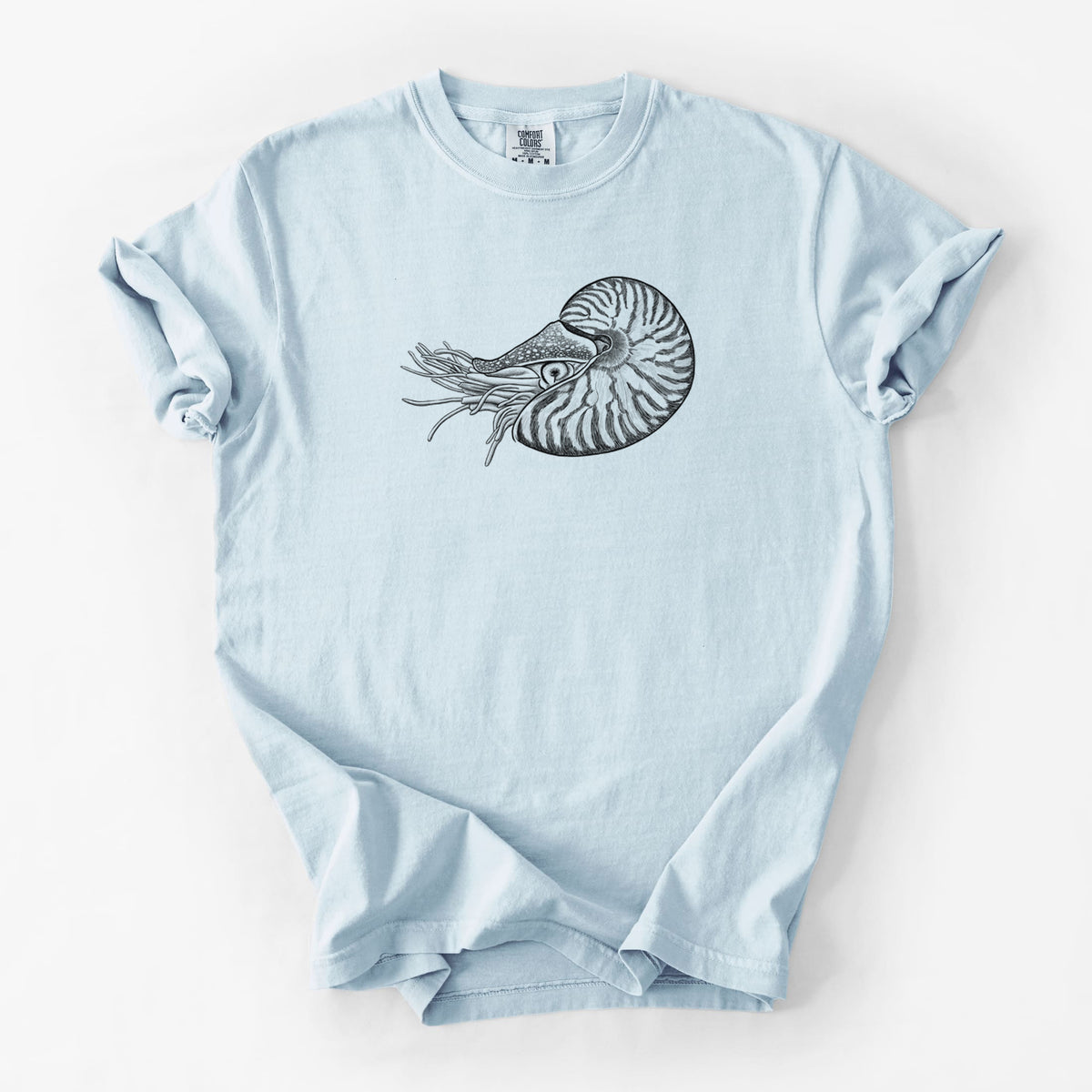 Chambray blue Comfort Colors t-shirt laid flat, printed with a detailed black ink illustration of a chambered nautilus with its striped spiral shell and tentacles.