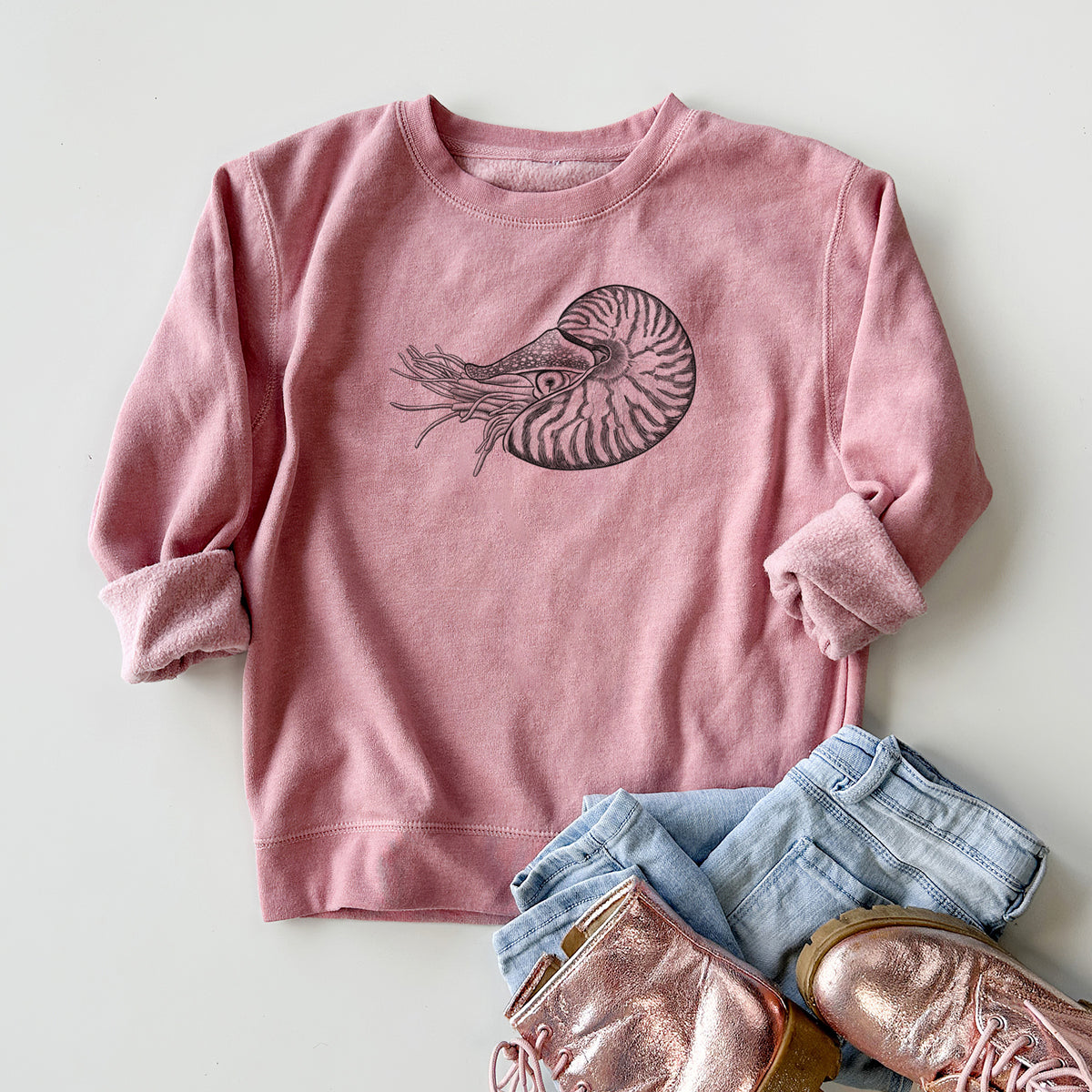 Youth crewneck sweatshirt printed with a detailed black ink illustration of a chambered nautilus with its striped spiral shell and tentacles, styled flat with jeans and boots.