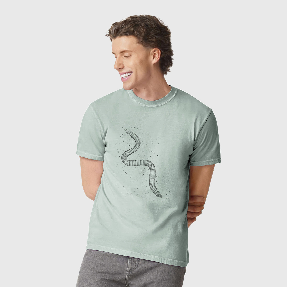 Man wearing a Comfort Colors t-shirt printed with a black ink illustration of a nightcrawler earthworm with soil specks.