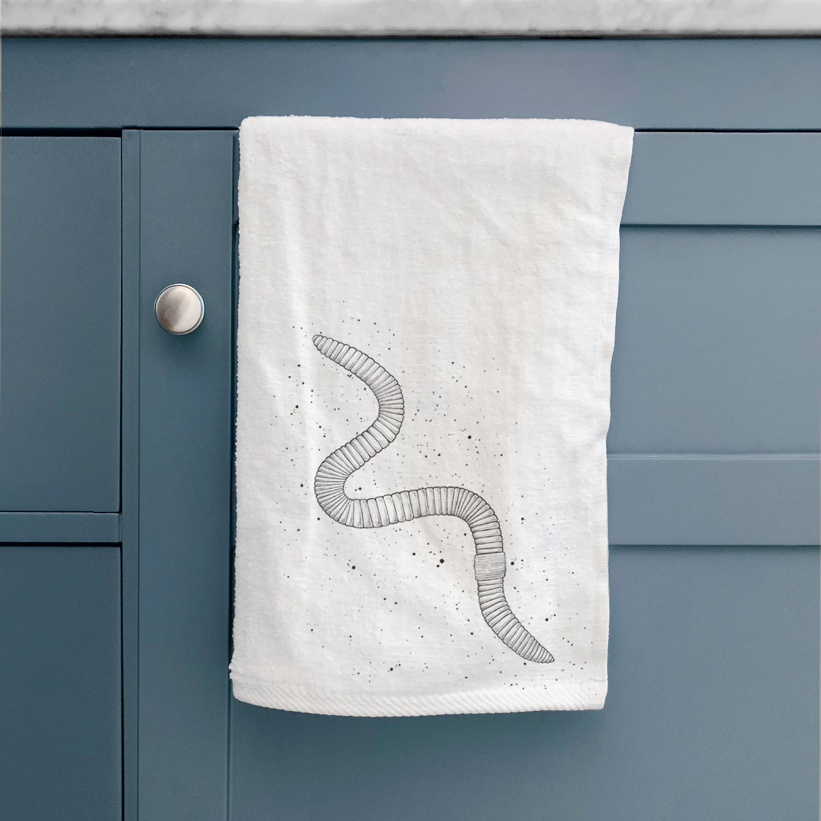 White hand towel printed with a black ink illustration of a nightcrawler earthworm with soil specks.