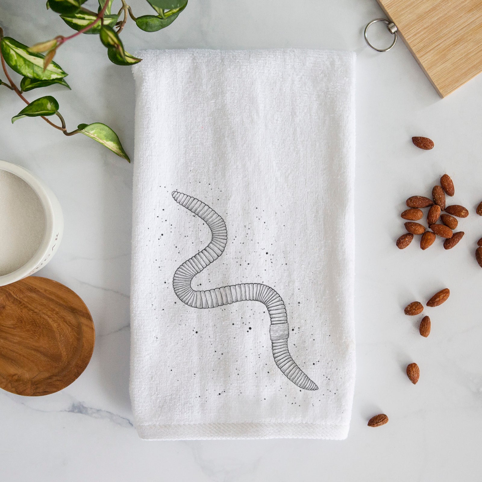 White hand towel printed with a black ink illustration of a nightcrawler earthworm with soil specks.