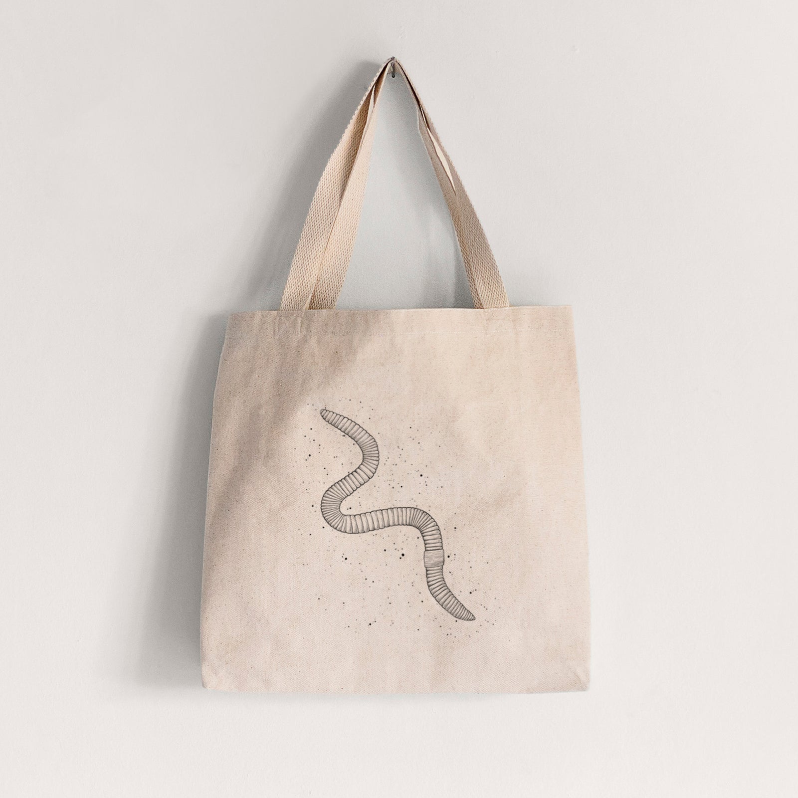 Natural canvas tote bag printed with a black ink illustration of a nightcrawler earthworm with soil specks.