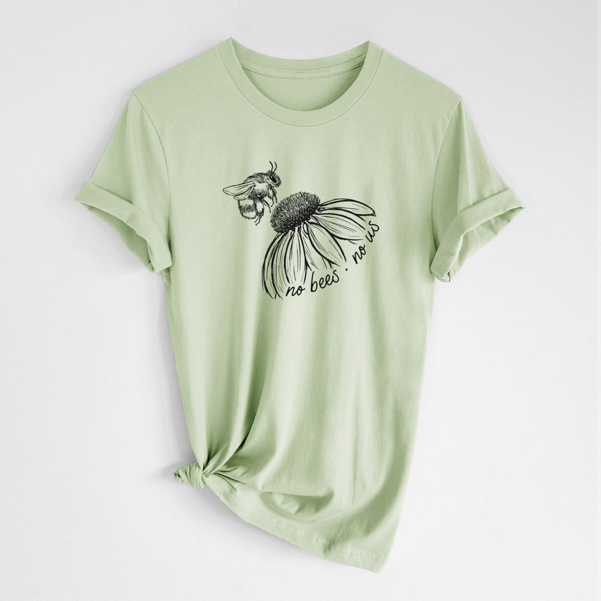 Spring green lightweight cotton t-shirt laid flat with the sleeves rolled, printed with a black ink illustration of a bee flying toward a coneflower, with the handwritten words no bees no us.