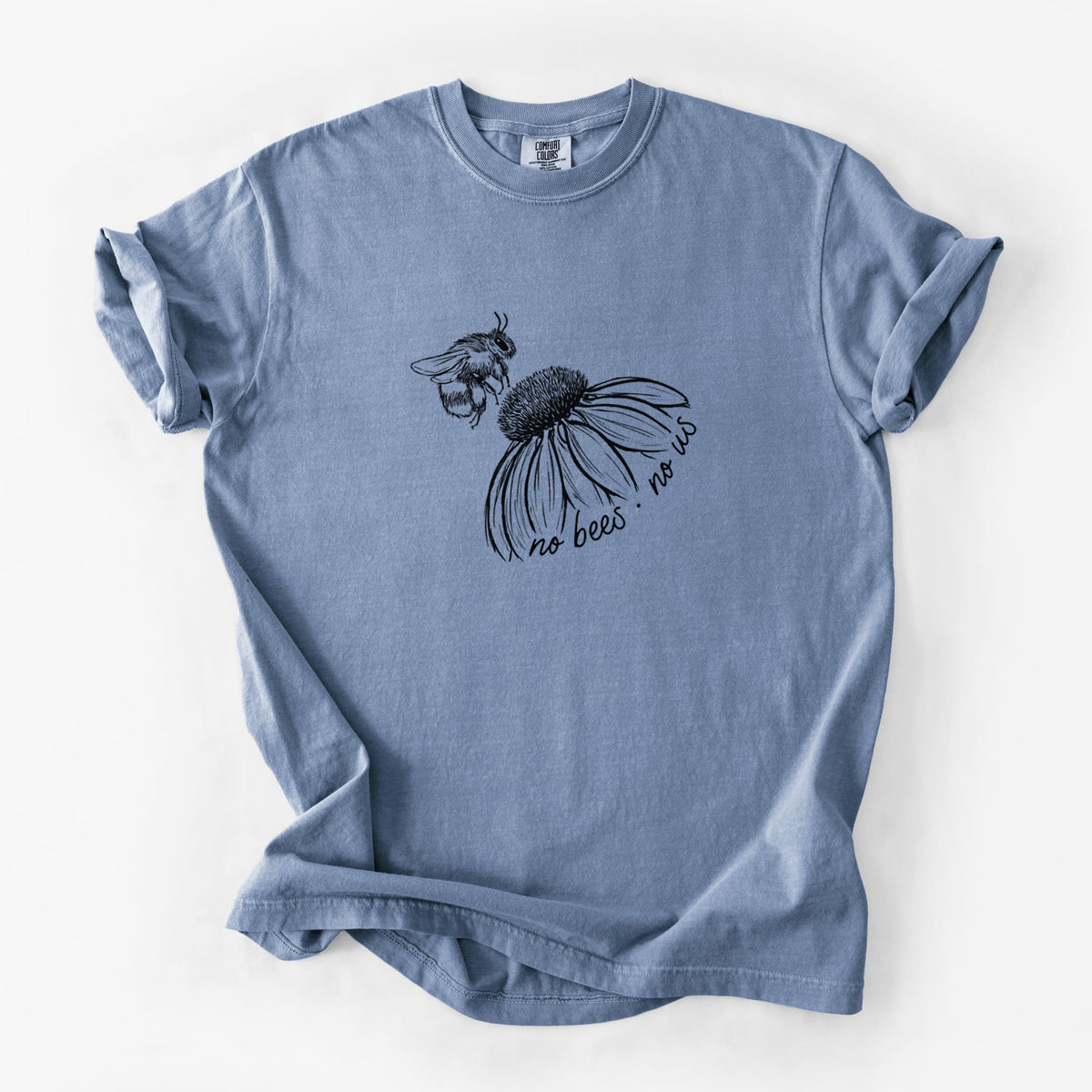 Blue jean Comfort Colors t-shirt laid flat, printed with a black ink illustration of a bee flying toward a coneflower, with the handwritten words no bees no us.
