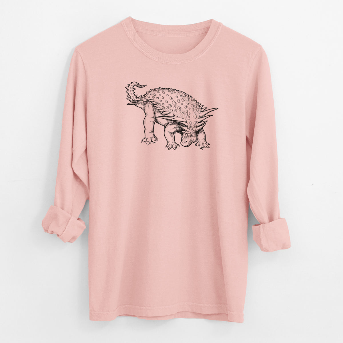 Peachy Comfort Colors long sleeve shirt laid flat with the cuffs rolled, printed with a black ink illustration of an armored Nodosaurus.