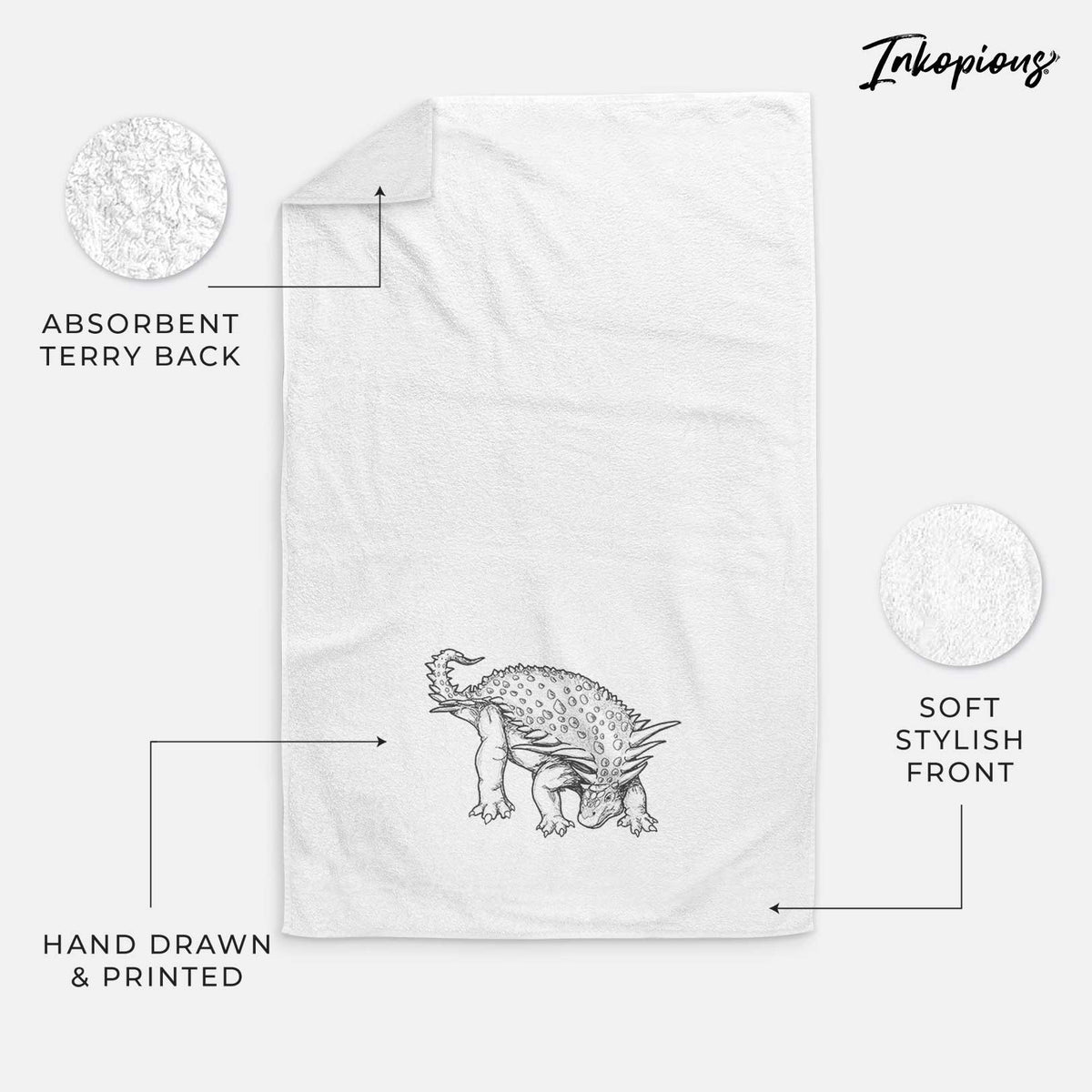 White hand towel printed with a black ink illustration of an armored Nodosaurus.