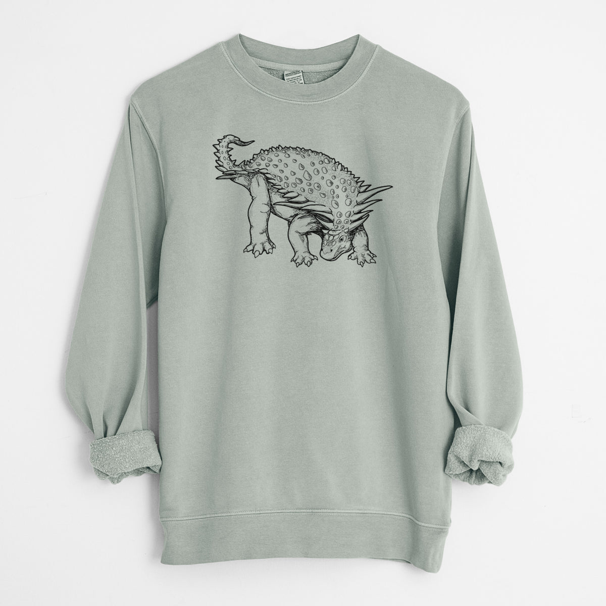 Sage green pigment dyed crewneck sweatshirt laid flat with the sleeves rolled, printed with a black ink illustration of an armored Nodosaurus.