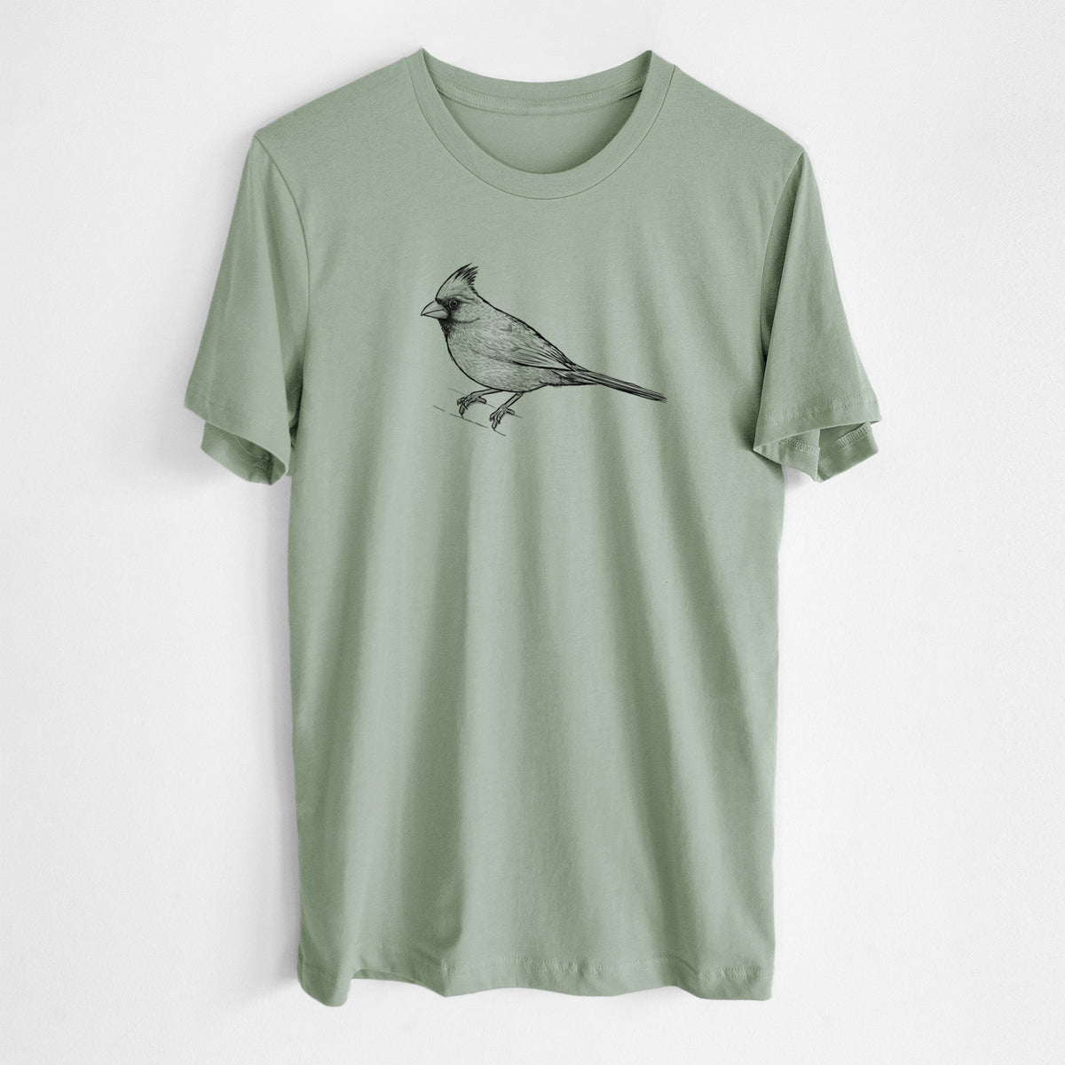 Sage green lightweight cotton t-shirt laid flat, printed with a detailed black ink sketch of a northern cardinal perched with its crest raised.