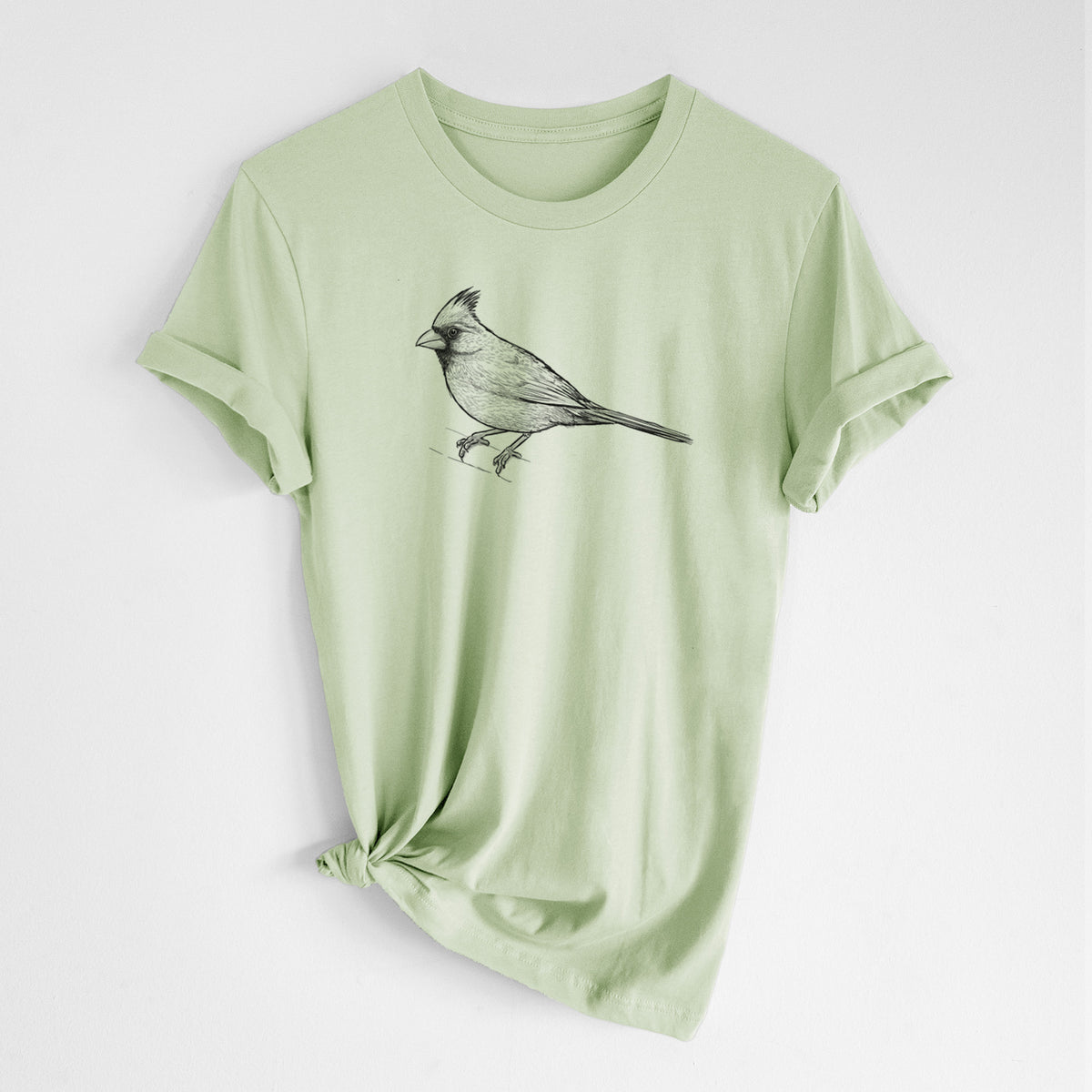 Spring green lightweight cotton t-shirt laid flat with the sleeves rolled, printed with a detailed black ink sketch of a northern cardinal perched with its crest raised.