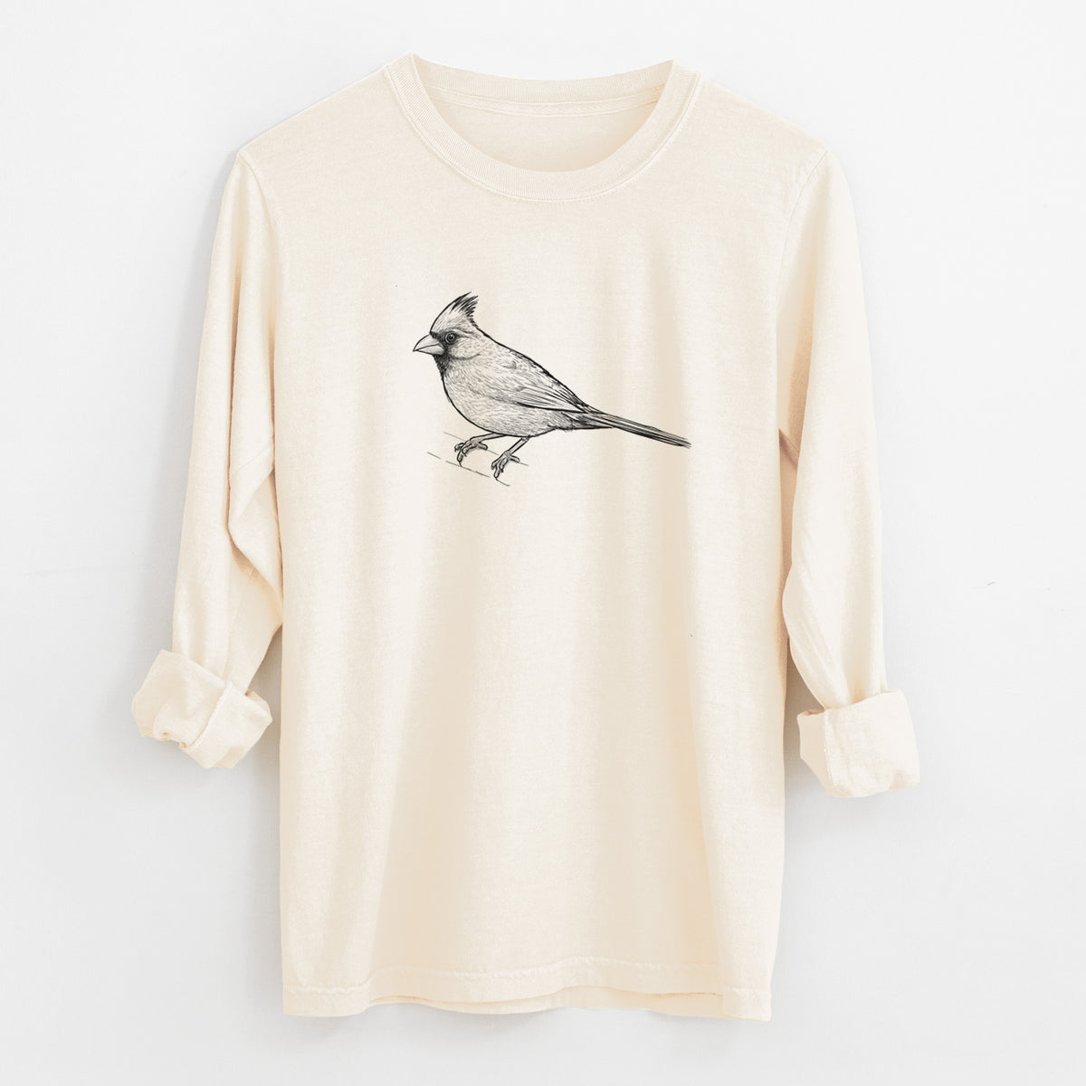 Ivory Comfort Colors long sleeve shirt laid flat with the cuffs rolled, printed with a detailed black ink sketch of a northern cardinal perched with its crest raised.
