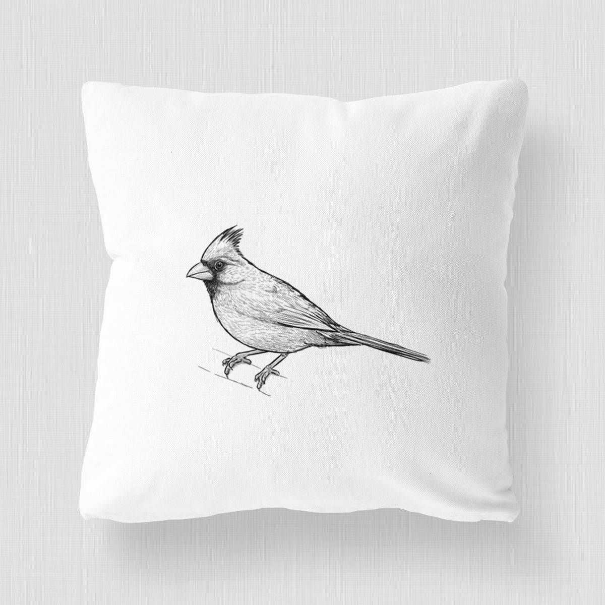 White pillow cover printed with a detailed black ink sketch of a northern cardinal perched with its crest raised.