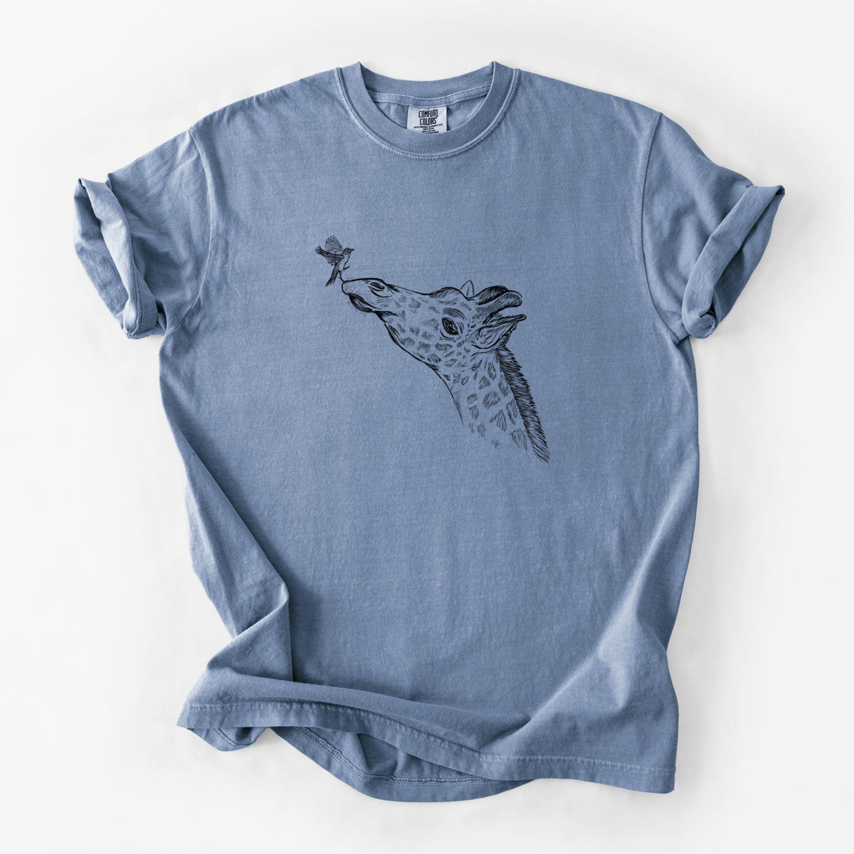 Blue jean Comfort Colors t-shirt laid flat, printed with a black ink illustration of a northern giraffe reaching its head up to nibble a flower.