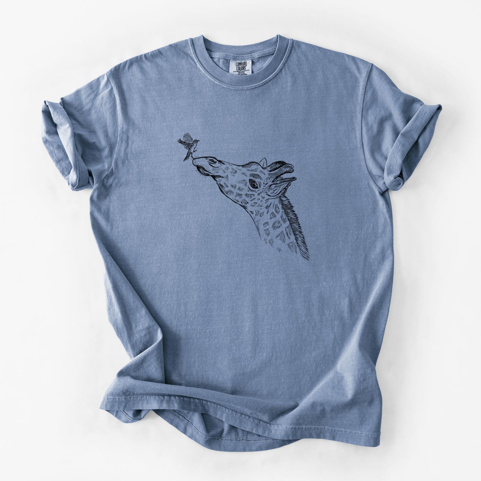 Blue jean Comfort Colors t-shirt laid flat, printed with a black ink illustration of a northern giraffe reaching its head up to nibble a flower.