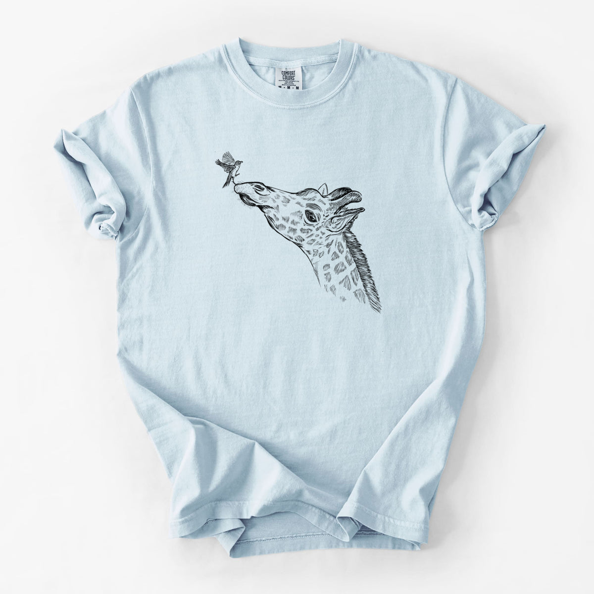 Chambray blue Comfort Colors t-shirt laid flat, printed with a black ink illustration of a northern giraffe reaching its head up to nibble a flower.