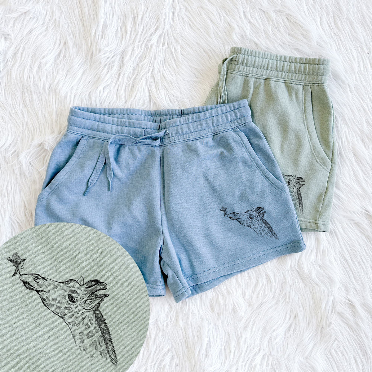 Two pairs of Cali Wave shorts in different colors printed with a black ink illustration of a northern giraffe reaching its head up to nibble a flower, with a close-up of the print.