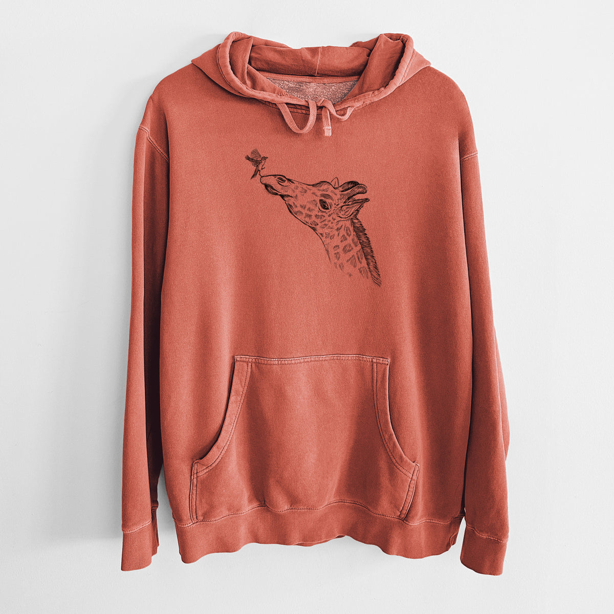 Amber orange pigment dyed hoodie laid flat, printed with a black ink illustration of a northern giraffe reaching its head up to nibble a flower.