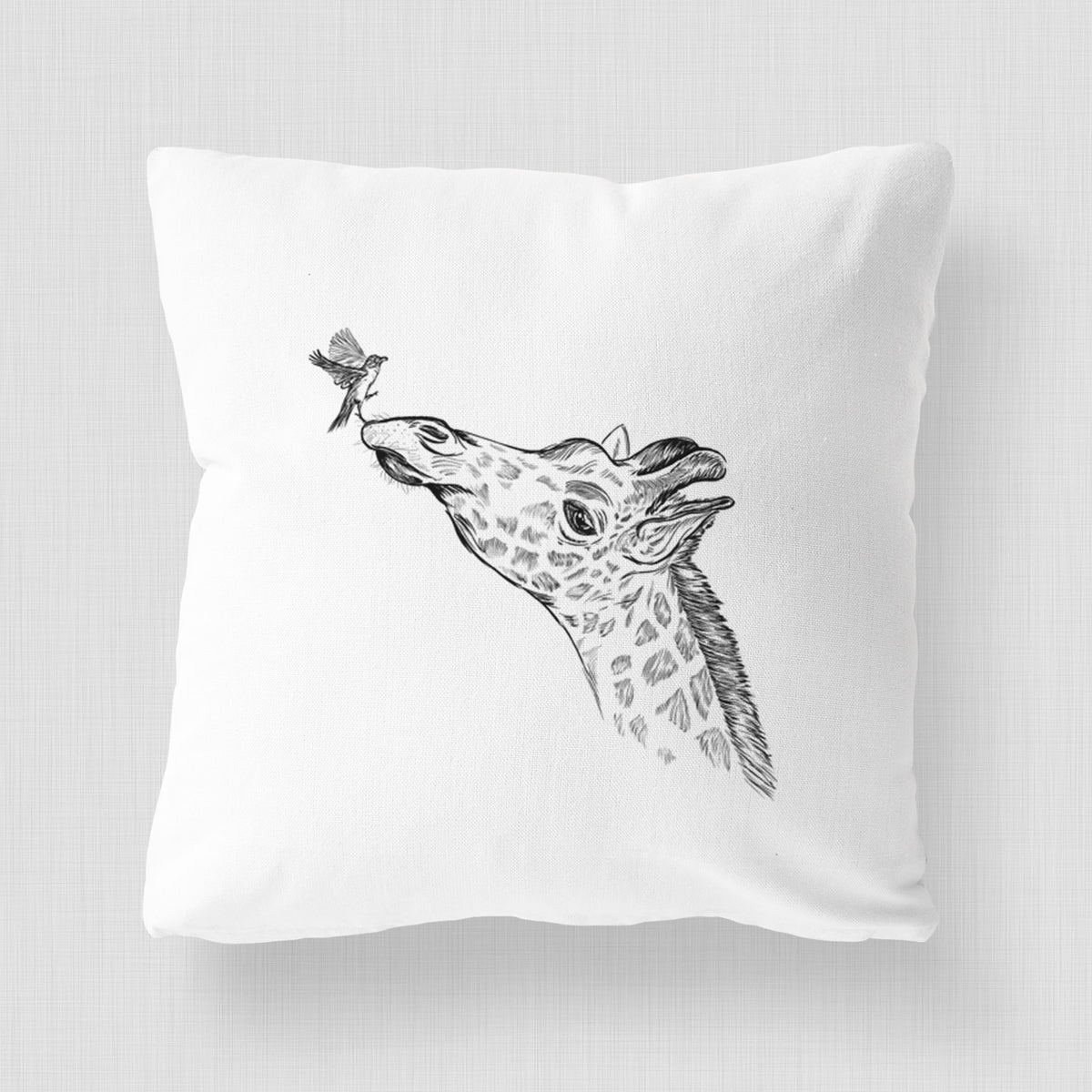 White pillow cover printed with a black ink illustration of a northern giraffe reaching its head up to nibble a flower.