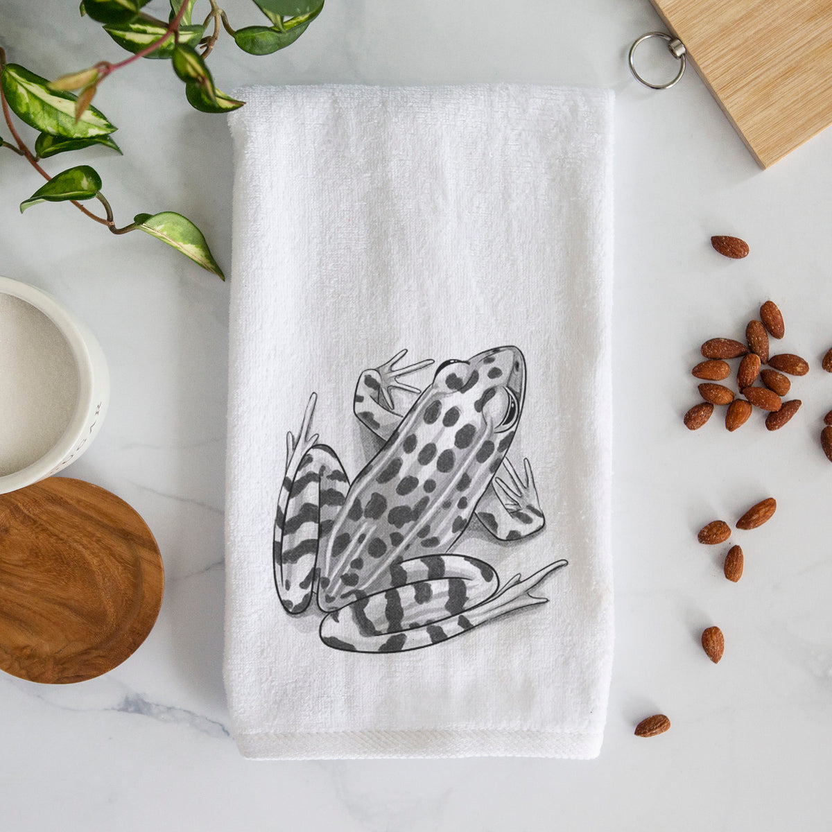 White hand towel printed with a detailed black ink illustration of a spotted northern leopard frog.