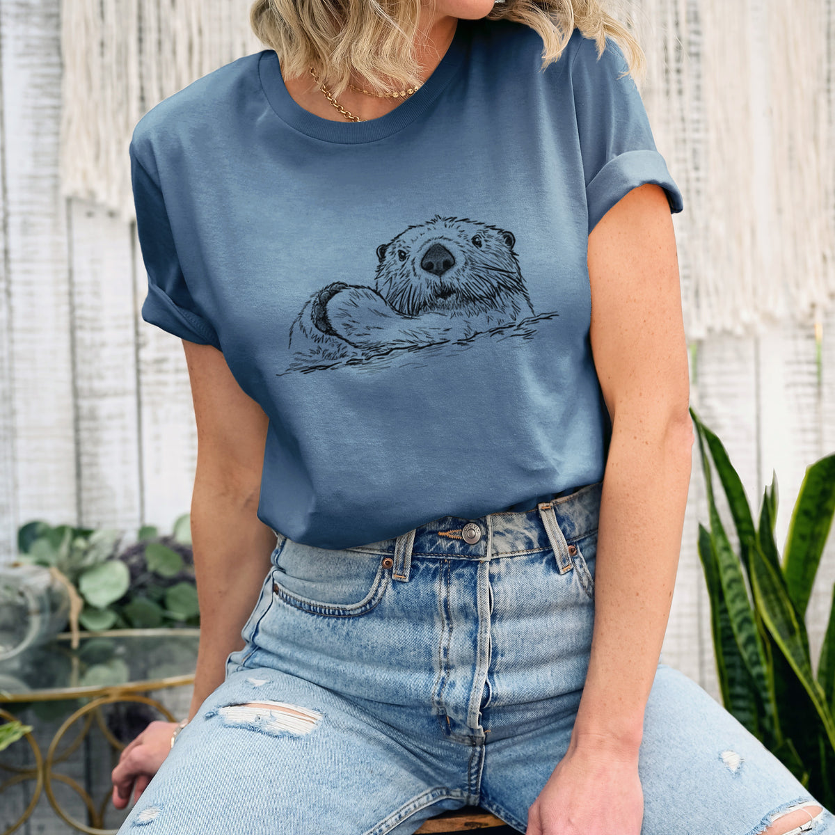Woman wearing a steel blue lightweight cotton t-shirt printed with a black ink illustration of a northern river otter peeking out of the water.